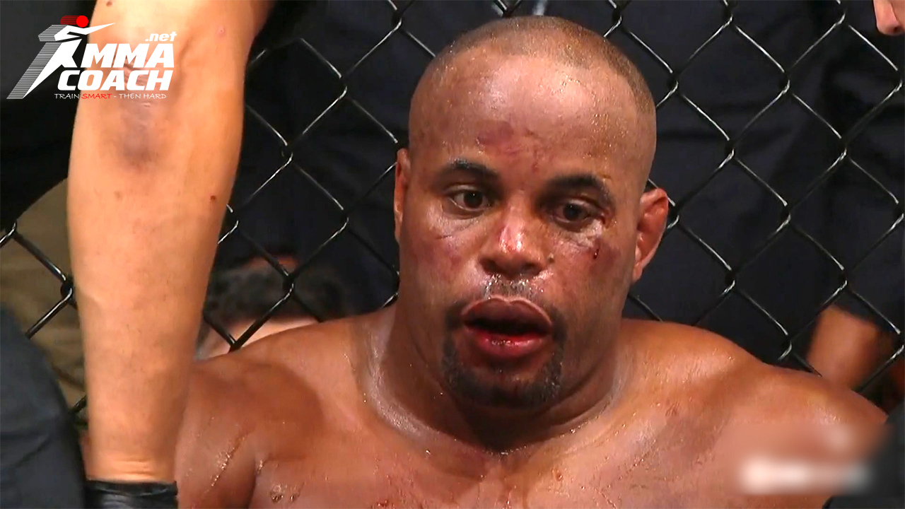 Daniel Cormier sitting against the cage defeated